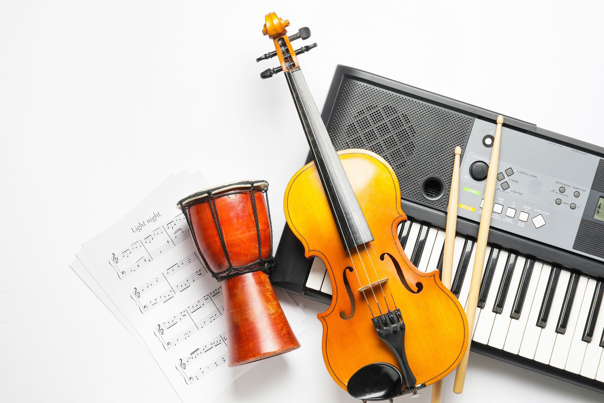 A violin , keyboard , drum and sheet music on a white background.