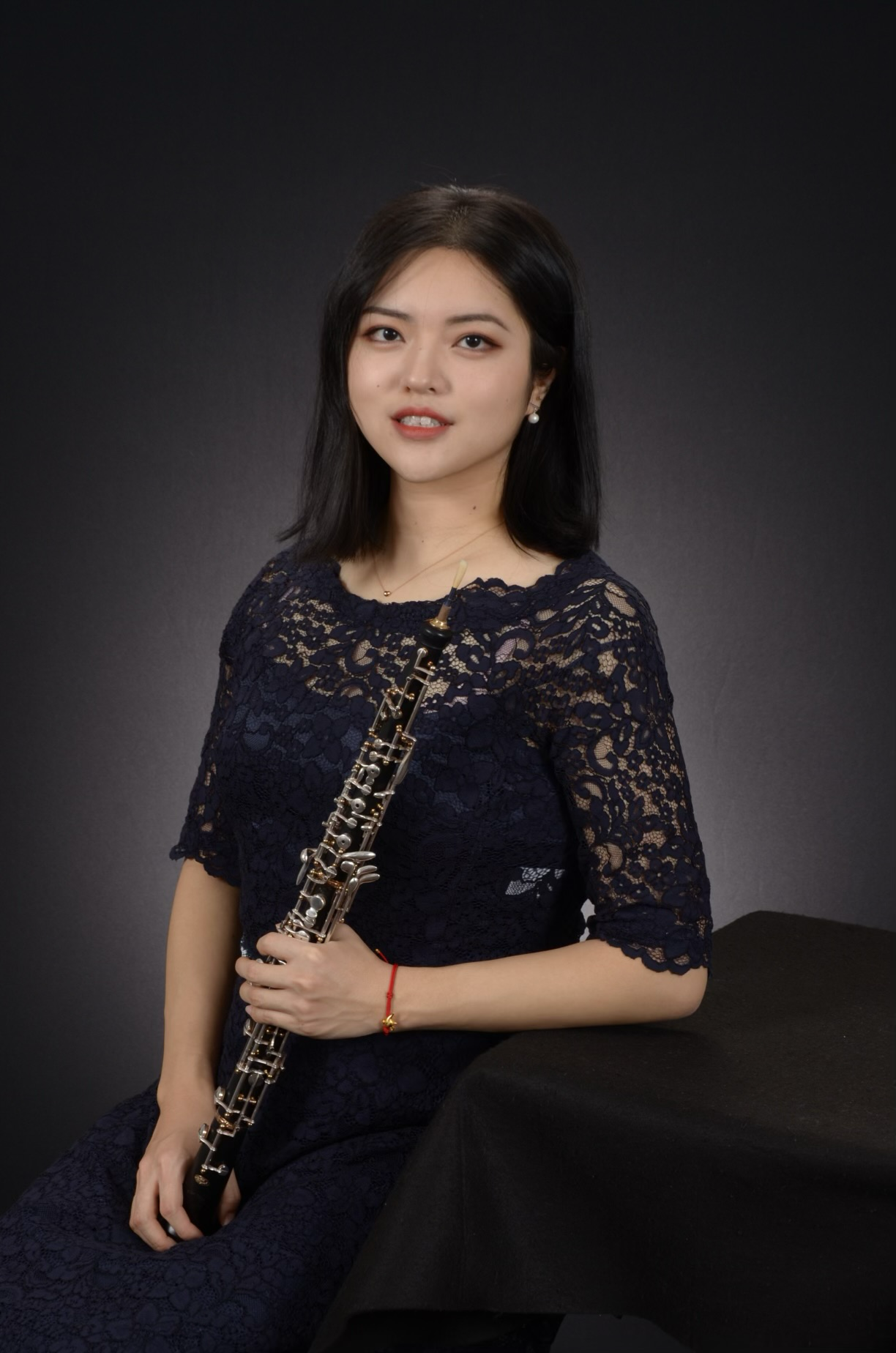 A woman in a blue dress is holding a clarinet.